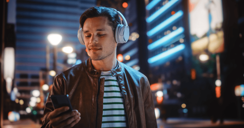 Man with headphones using phone app to trade on margin